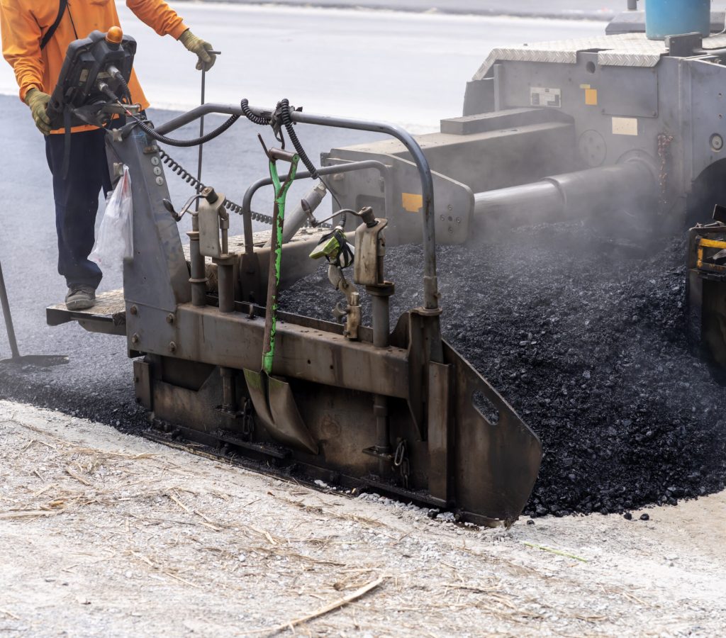 Machines are pouring asphalt to build roads for cars.